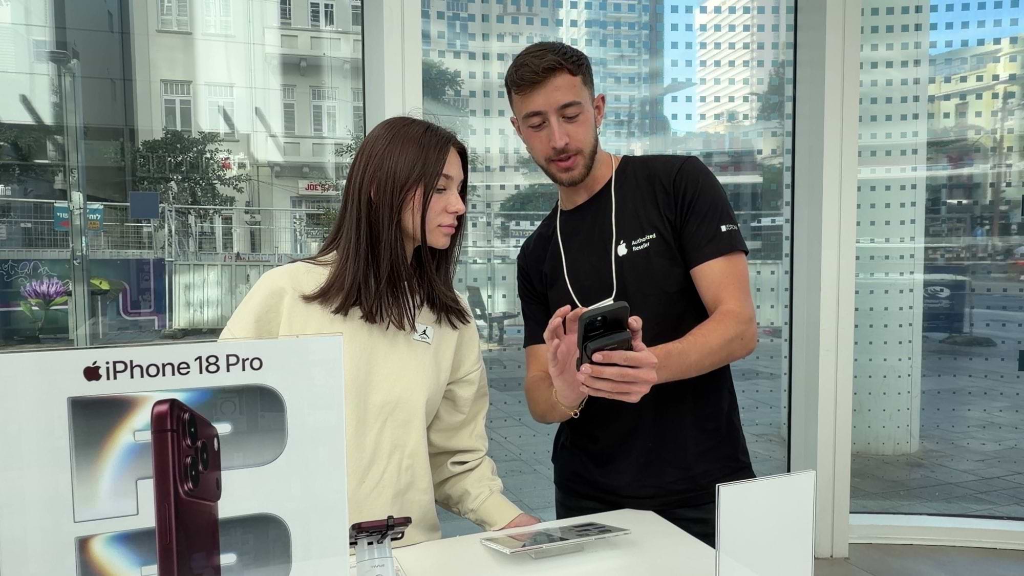 איש המכירות מראה ללקוחה את imPos על ה-iPhone שבידו, בסניף רוטשילד