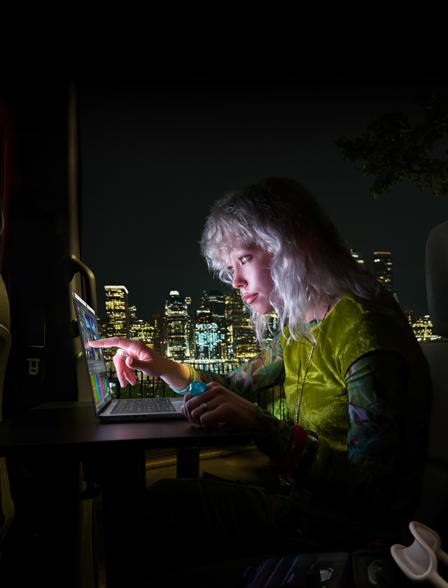 אישה עובדת על MacBook Pro בלילה מול נוף עירוני